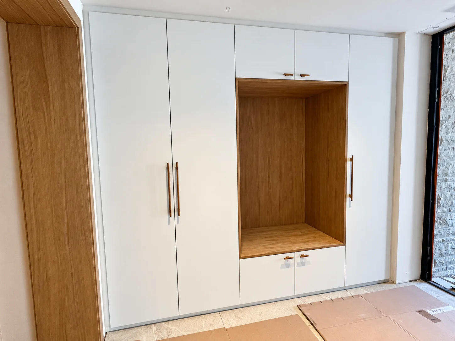 Placards blancs sur mesure avec niche et banc en bois dans une entrée